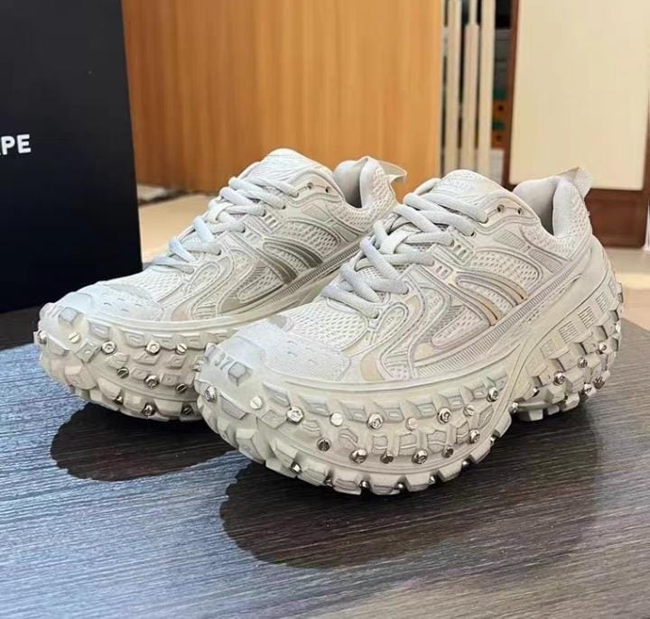 White studded chunky sneakers on red tray.