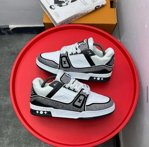White and black Louis Vuitton sneakers on red tray with boxes.