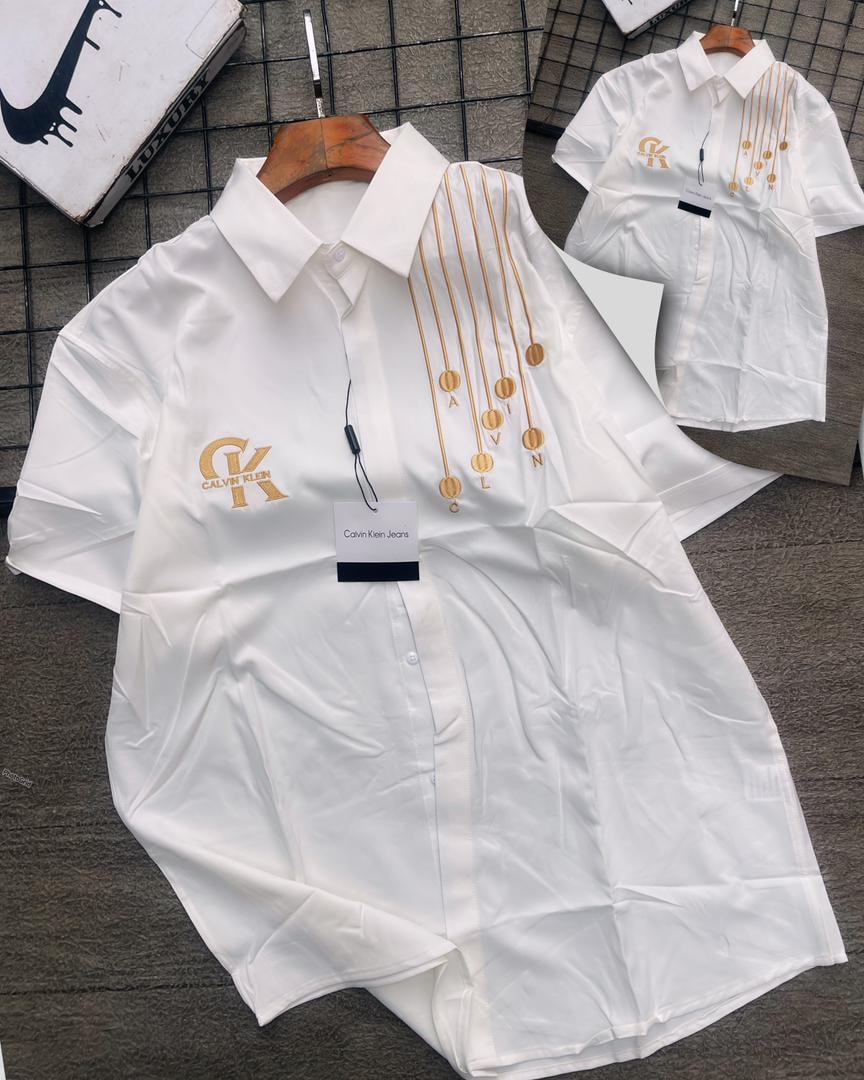 White Calvin Klein short sleeve shirt with gold medallions.