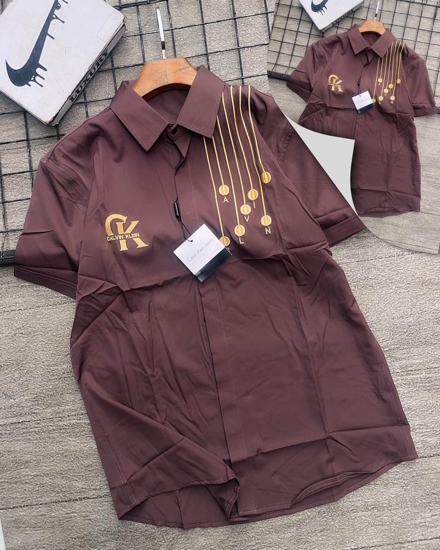 Brown Calvin Klein short sleeve shirt with gold medallions.