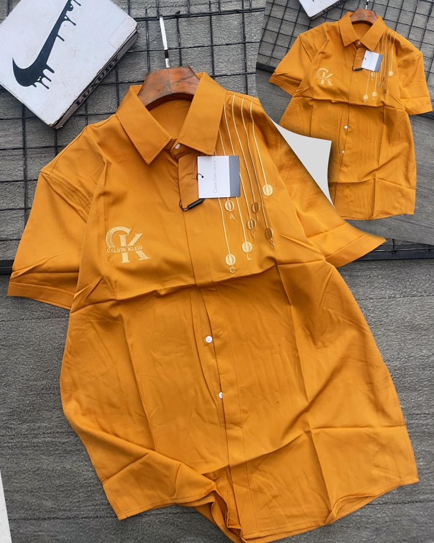 Orange Calvin Klein short sleeve shirt with gold medallions.