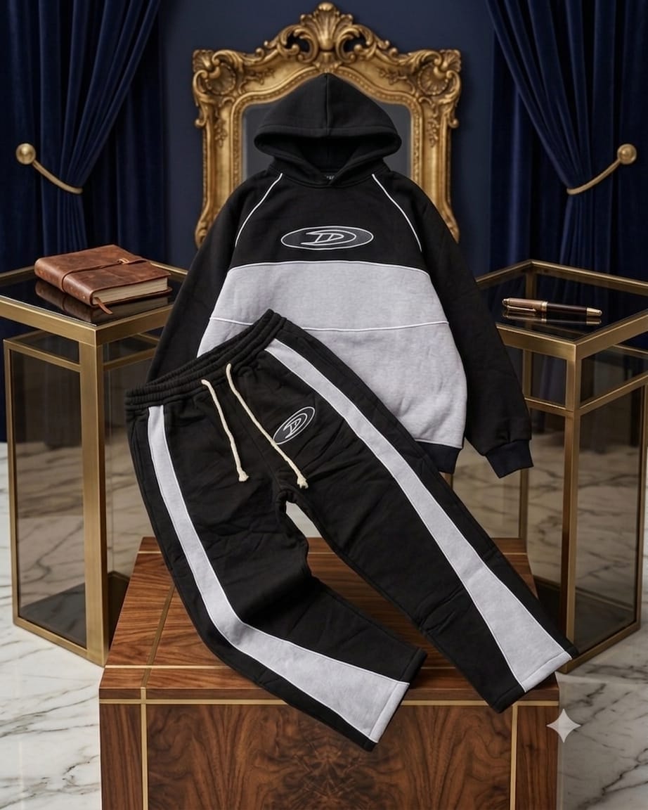 Black colorblock hooded two-piece tracksuit styled on wooden block with gold decor.