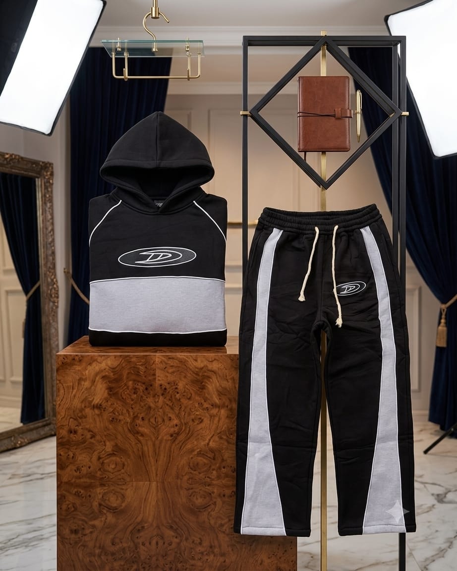 Black and gray colorblock hoodie with matching striped joggers on wooden display pedestal.