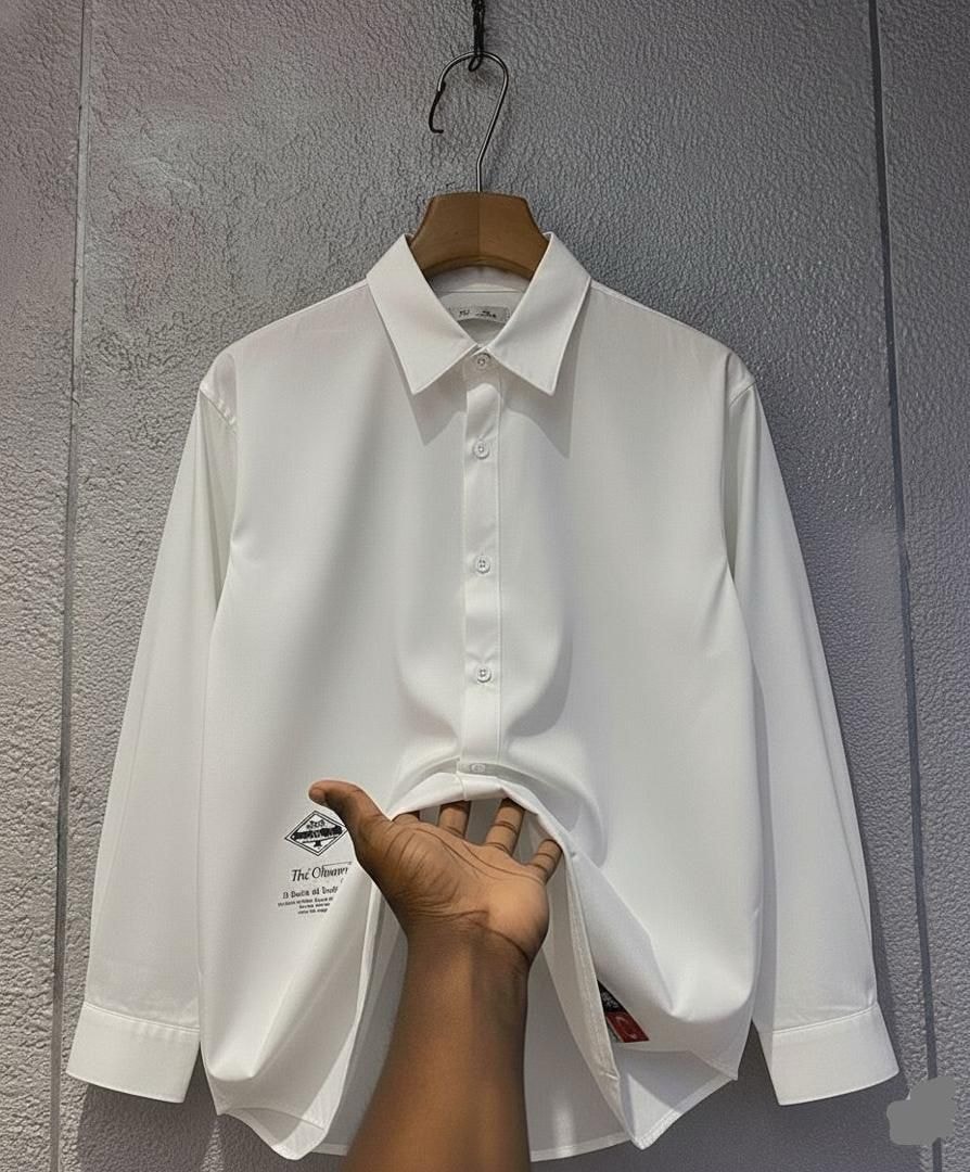 White long sleeve button-down shirt displayed on hanger against wall.