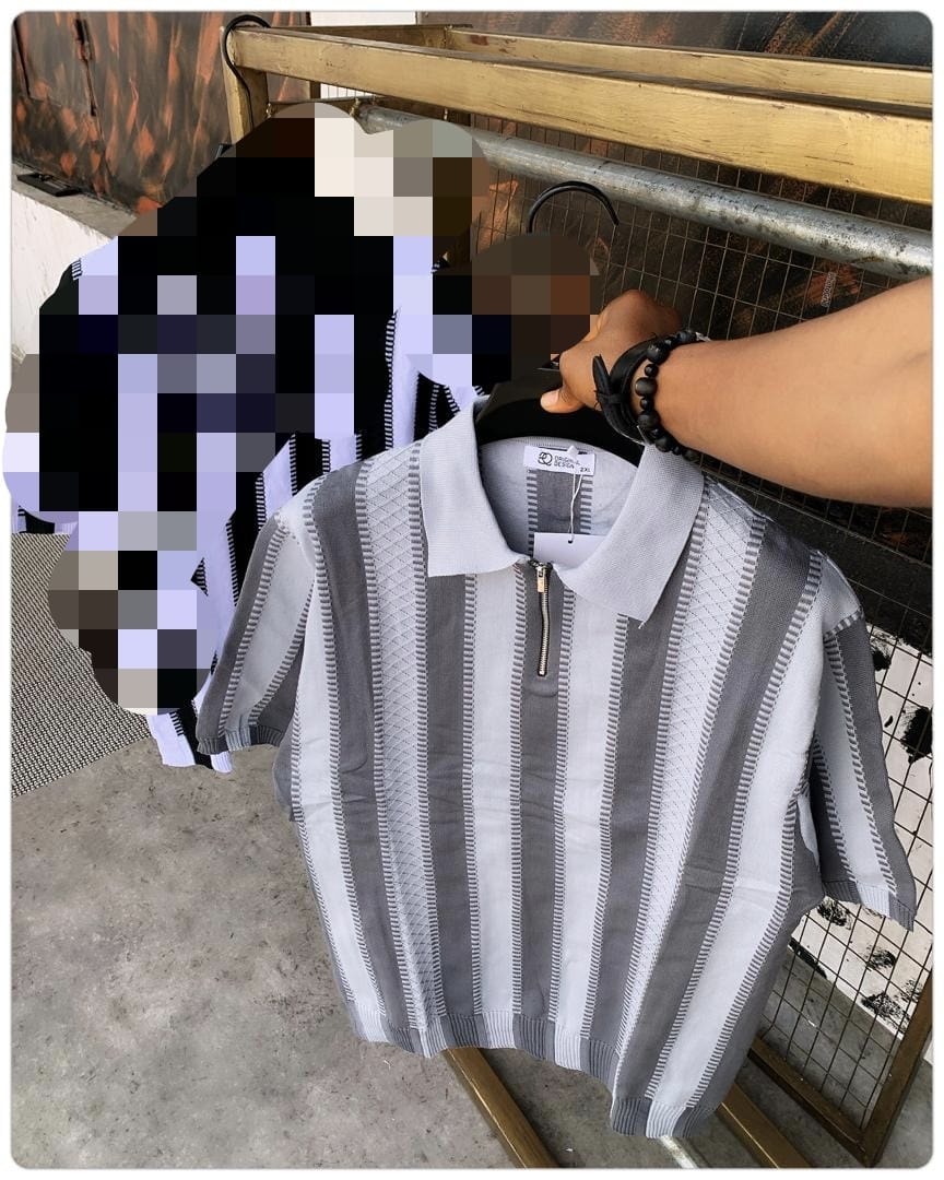 Gray and white vertically striped knit polo shirt held on hanger outdoors.