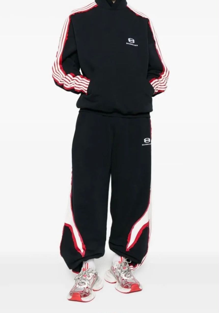 Model wearing black Balenciaga tracksuit with red and white stripes and logo.