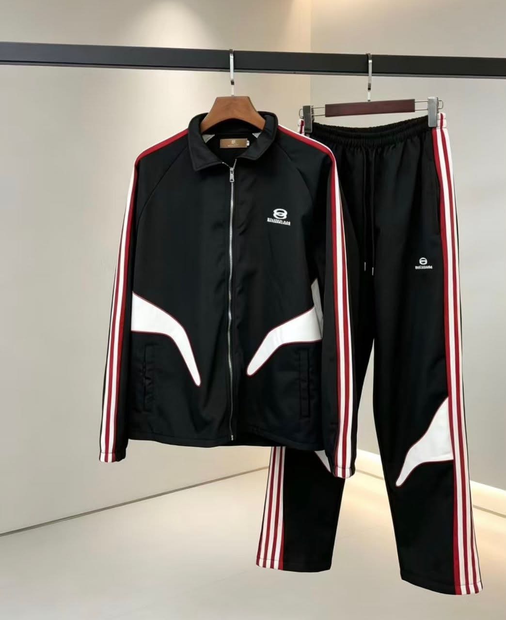 Black Balenciaga tracksuit with red and white stripes hanging on a rack.