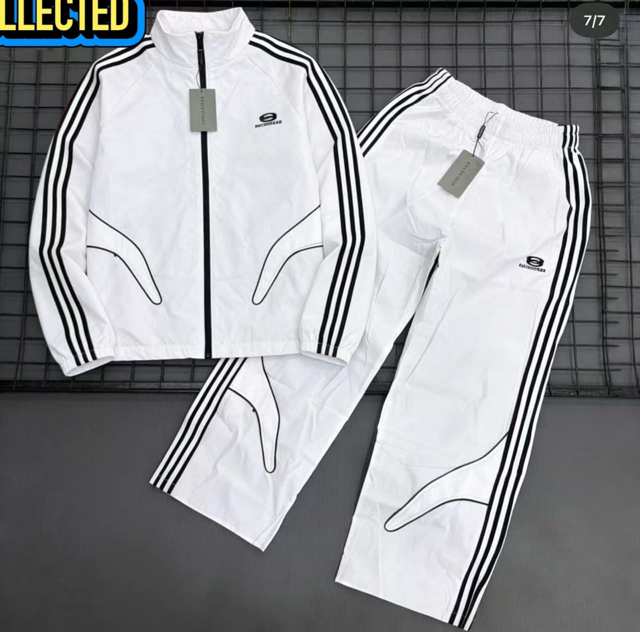 White Balenciaga tracksuit set with black stripes laid flat on a grid background.