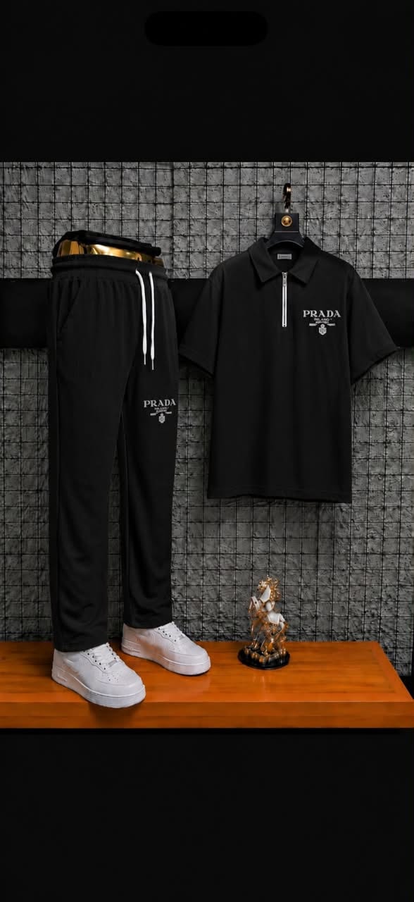 Black ribbed polo and jogger two-piece set styled on wooden surface with accessories.