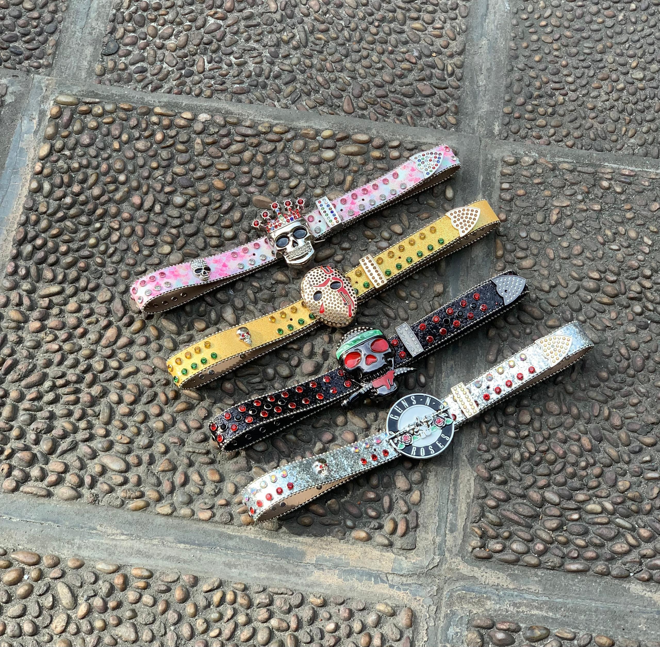 Four glitter belts with skull jason and crown buckles in bright colors.