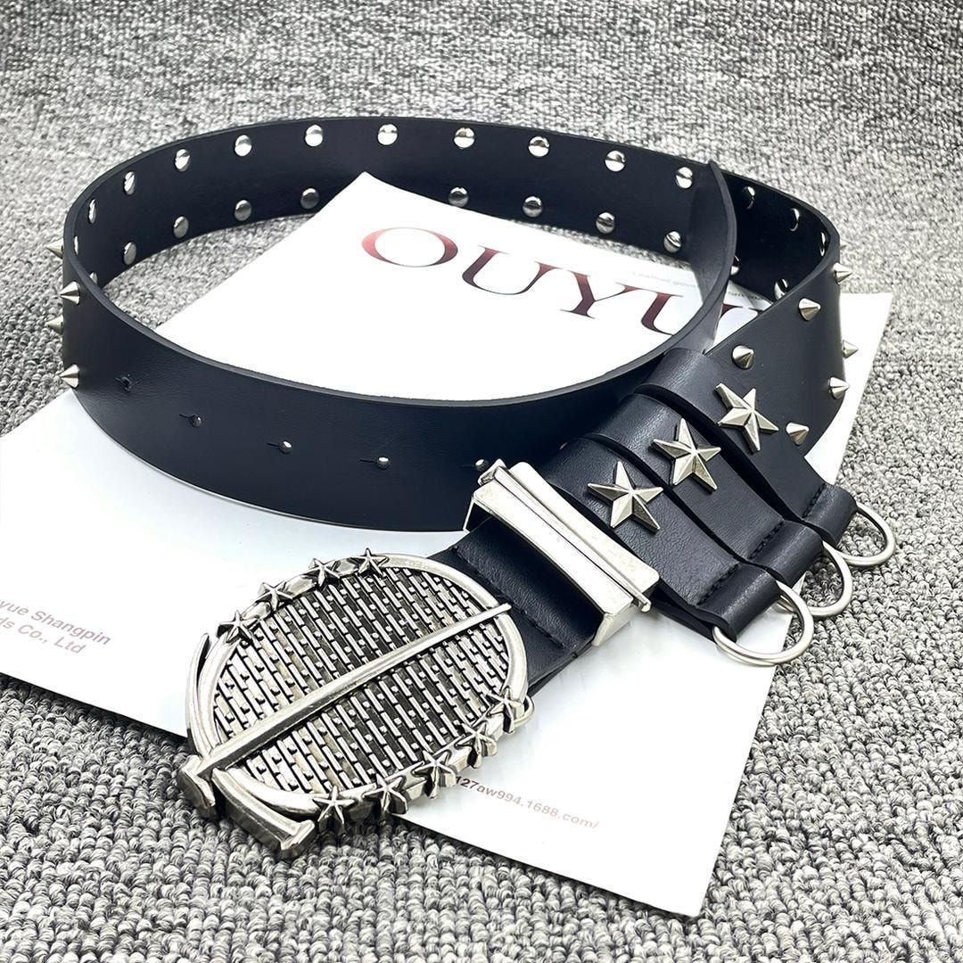 Black studded leather belt with star details and large decorative buckle displayed on a textured surface.