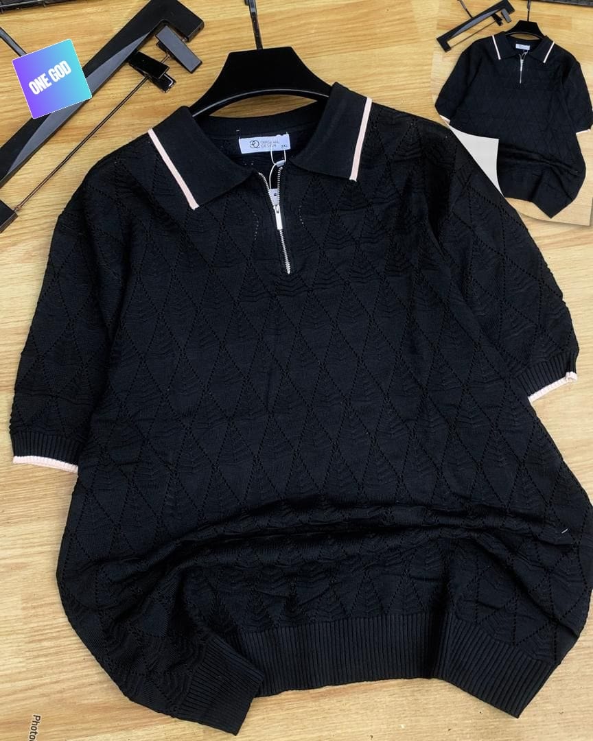 Black diamond knit quarter-zip polo with light trim on wooden background.