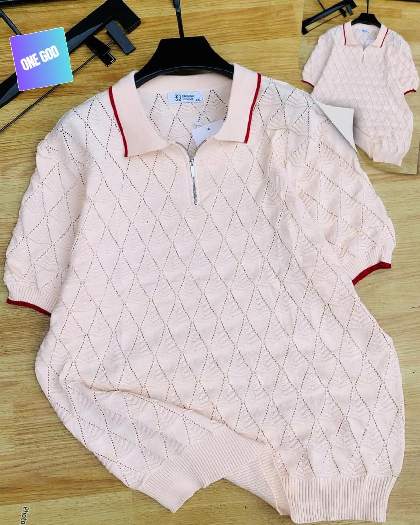 Light pink diamond knit quarter-zip polo with red trim on wooden background.