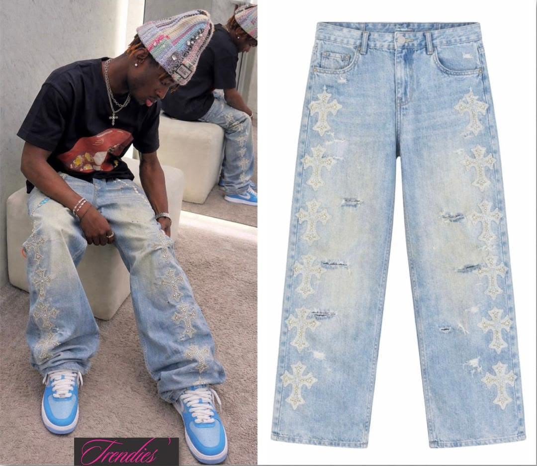 Man seated wearing light blue rhinestone cross baggy jeans with beanie and blue sneakers.