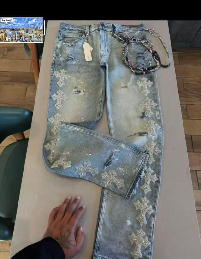 Flat lay of light blue distressed baggy jeans featuring white rhinestone crosses and rips.