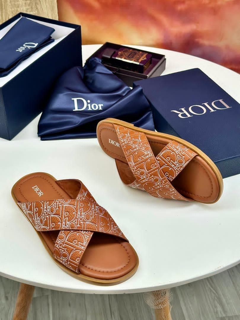 Brown Dior monogram slides with logo pattern displayed with blue boxes and accessories.