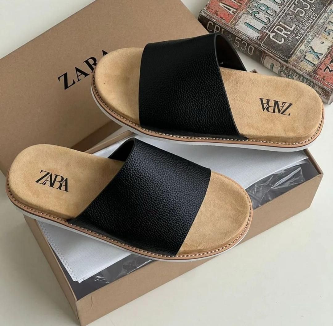 Black Zara slides with pebbled strap, beige insole and white sole displayed on a box.