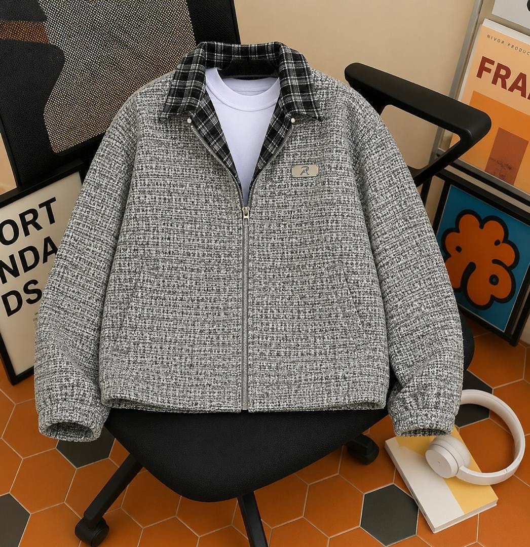 Gray tweed zip-up bomber jacket with plaid collar and ribbed hem, shown on a black chair.