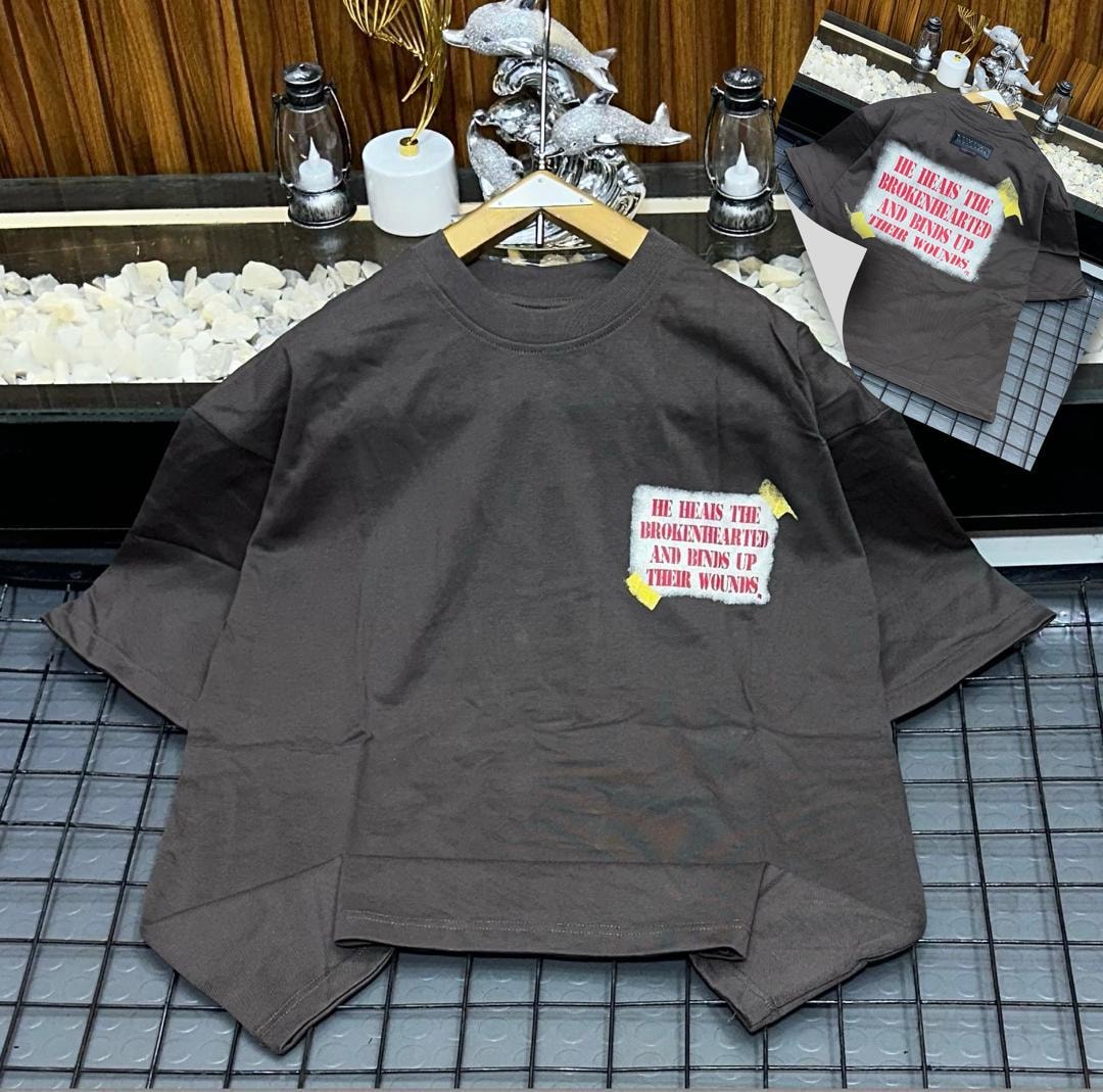 Brown oversized t-shirt with He Heals The Brokenhearted text patch on chest and back inset.