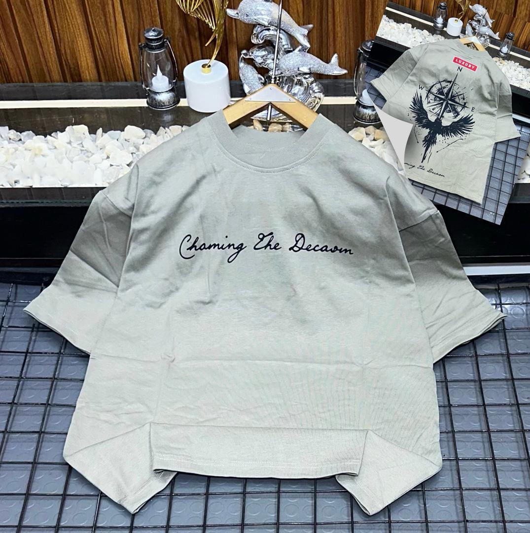 Olive oversized t-shirt with black cursive 'Chaming The Decaom' print on front and inset bird compass back view.