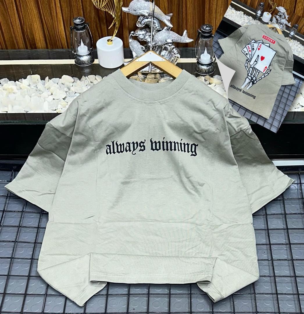 Beige oversized t-shirt with black 'always winning' gothic text on front and skeleton card graphic on back.