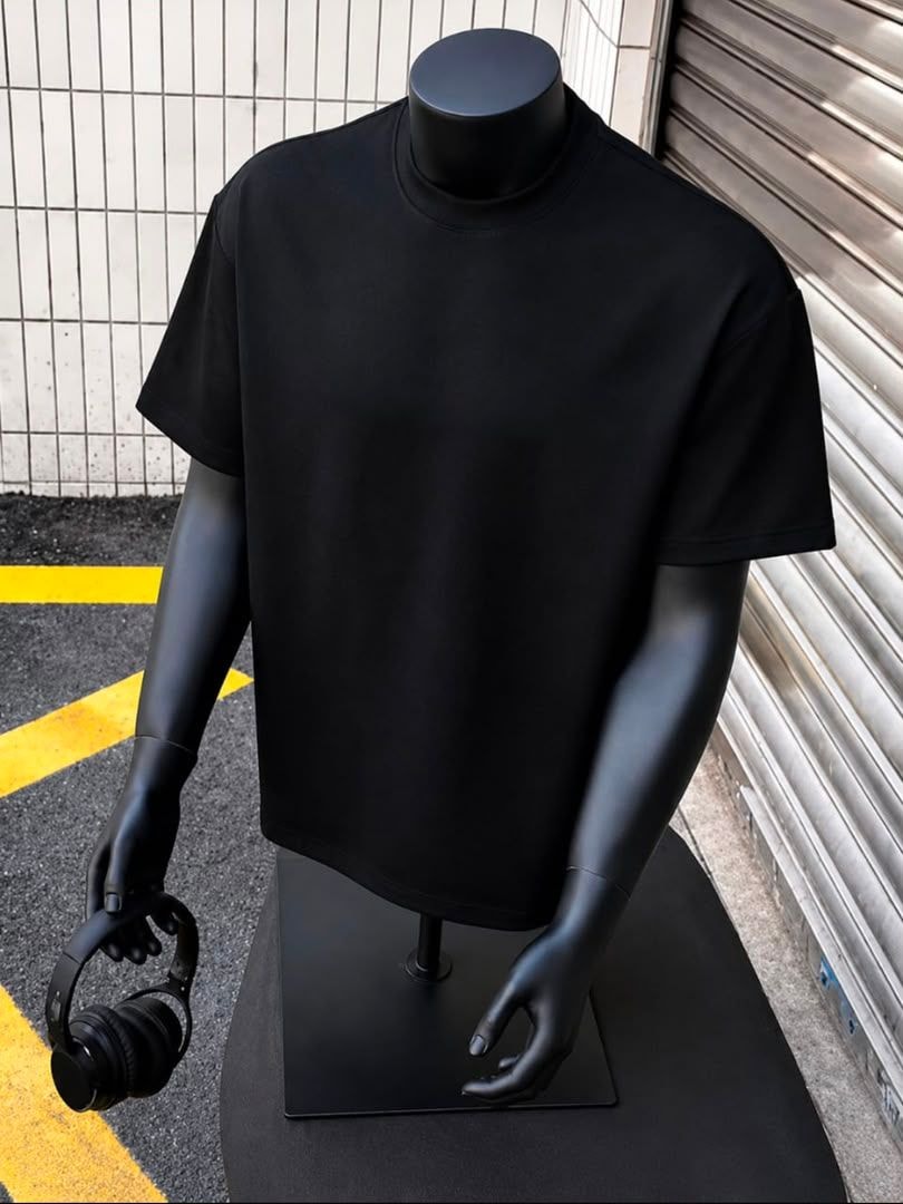 Black plain oversized t-shirt displayed on black mannequin outdoors.