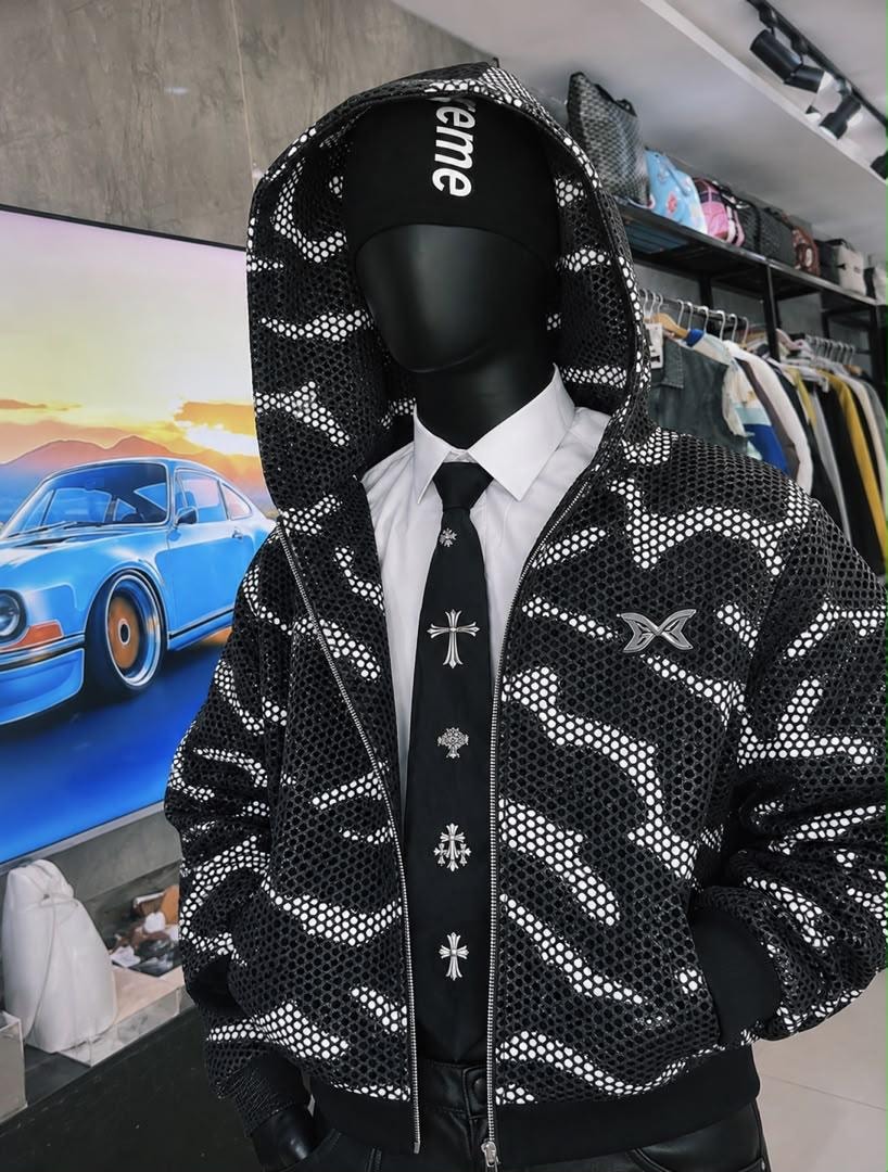 Mannequin wearing black camo mesh cropped hooded jacket with zip front and chest logo.