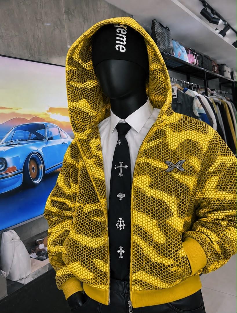 Mannequin wearing yellow camo mesh cropped hooded jacket with zip front and chest logo.