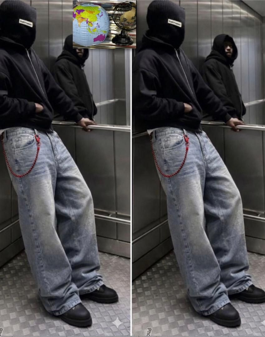Light blue baggy jeans with red beaded chain on model in elevator wearing black hoodie.
