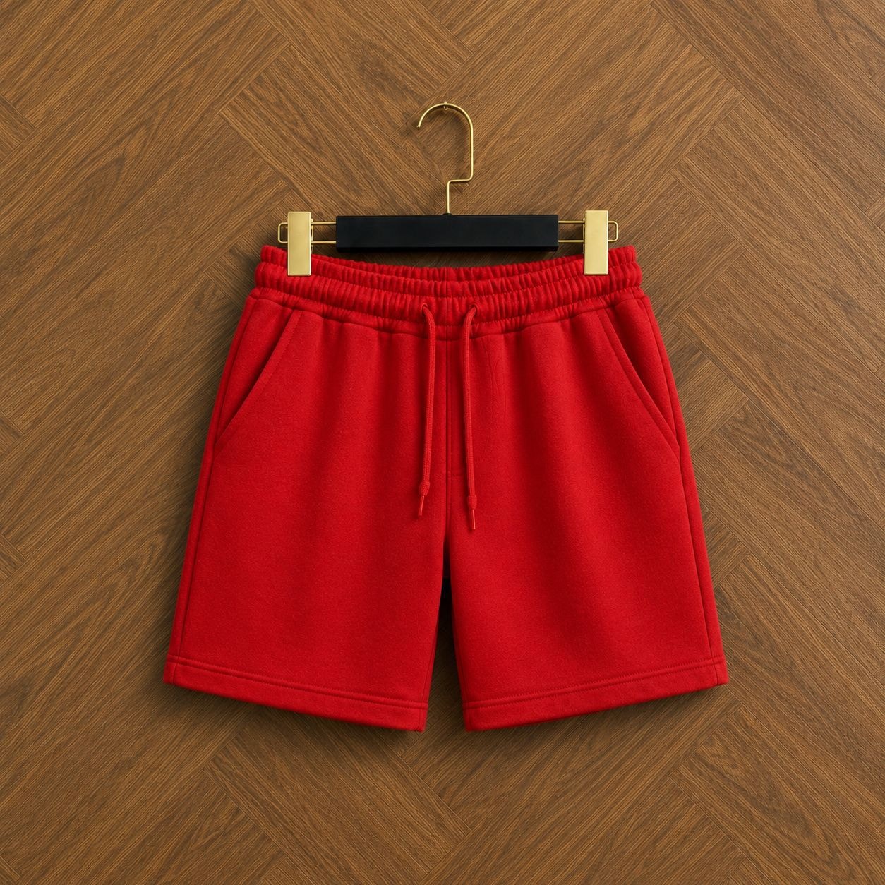 Red unisex fleece shorts front view hanging on wooden floor.