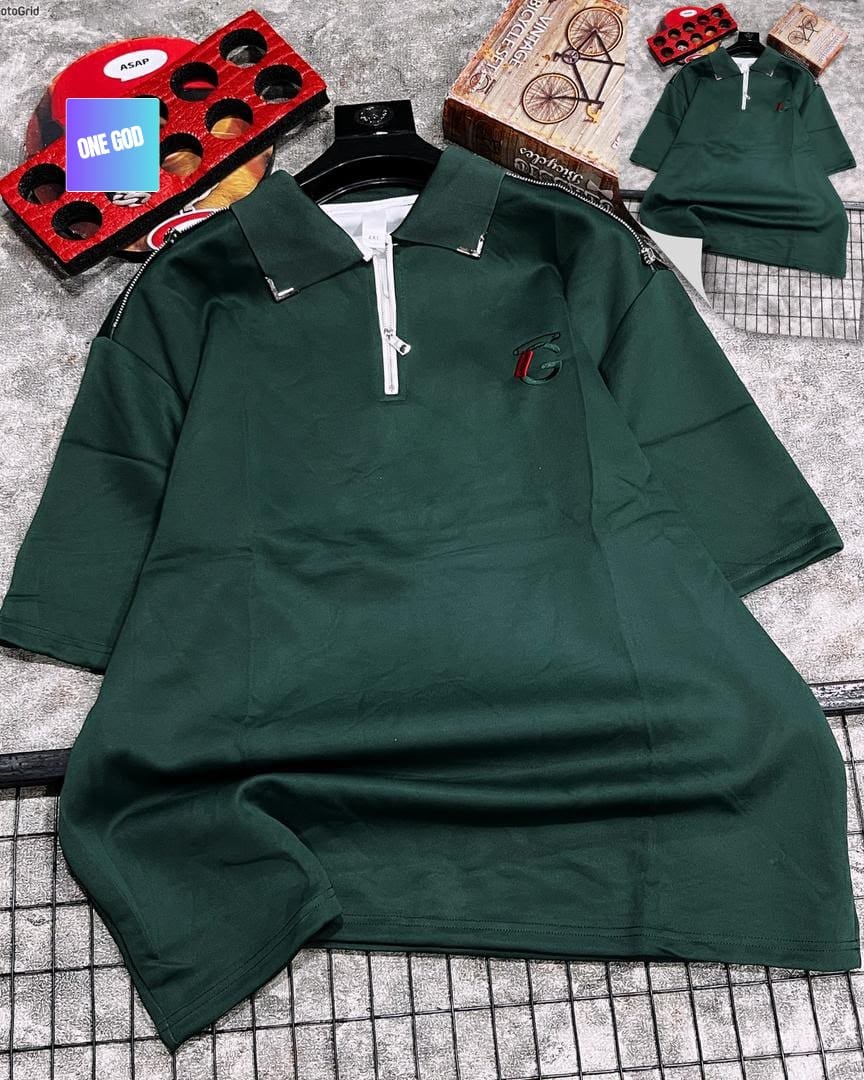 Green quarter-zip polo with shoulder zips and embroidered logo on grey background.