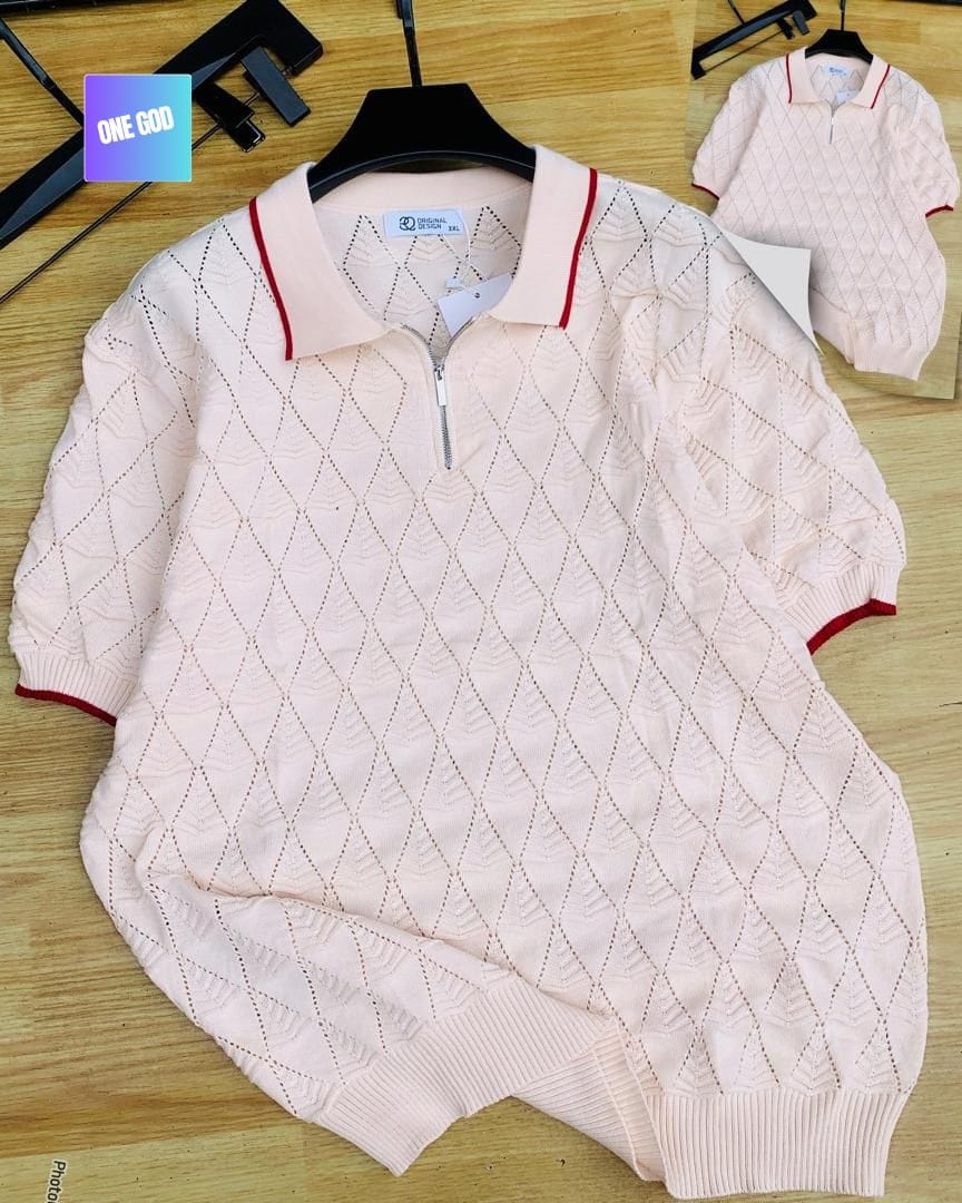 Light pink argyle knit quarter-zip polo shirt laid flat on wooden surface.
