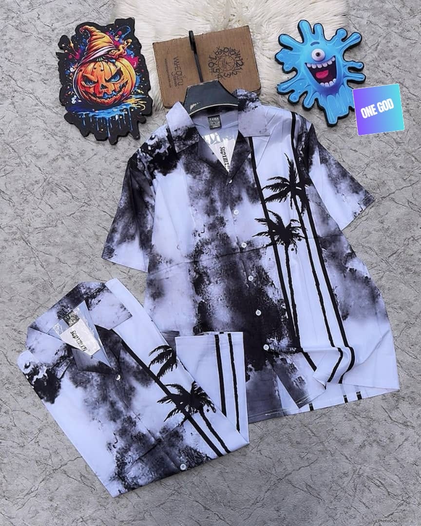 Short sleeve shirt with black palm trees on white and grey cloudy background, shown with folded pair.