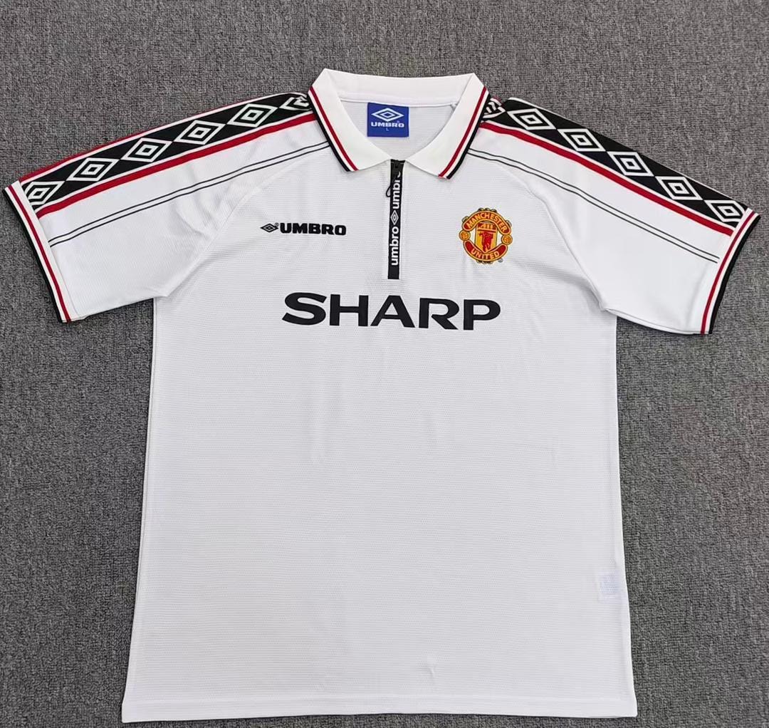 White vintage Manchester United Umbro Sharp jersey laid on gray surface.
