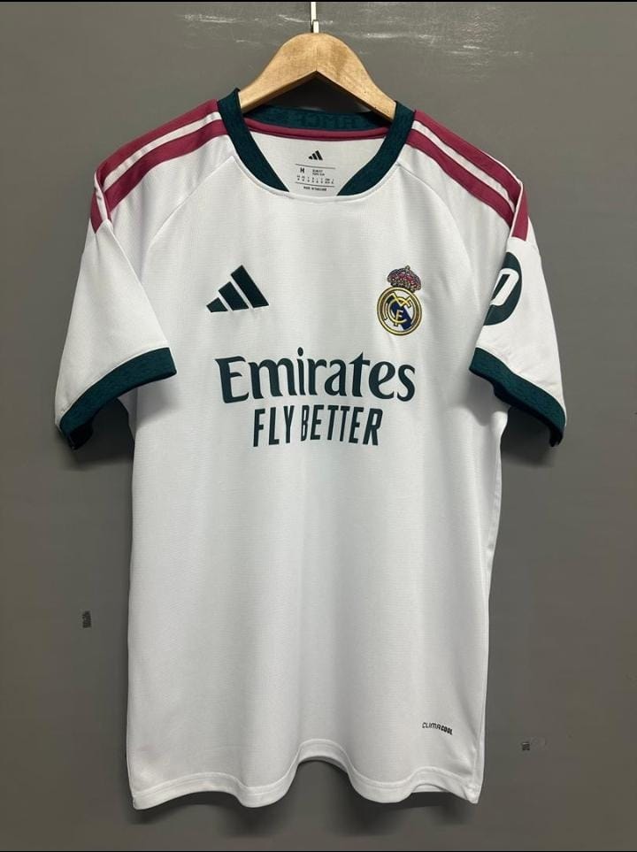 White Real Madrid Adidas Emirates football jersey on wooden hanger.