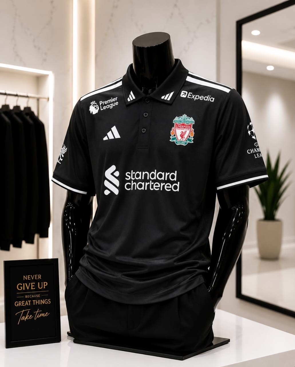 Black Liverpool FC polo jersey on a mannequin in a retail setting with accessories.