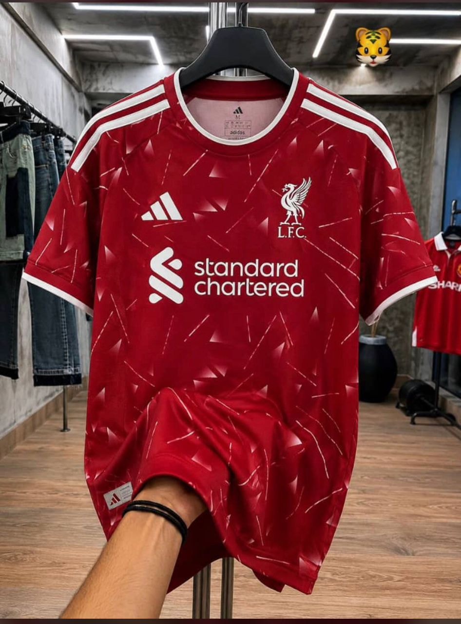 Red Liverpool FC adidas jersey held up in a store setting.