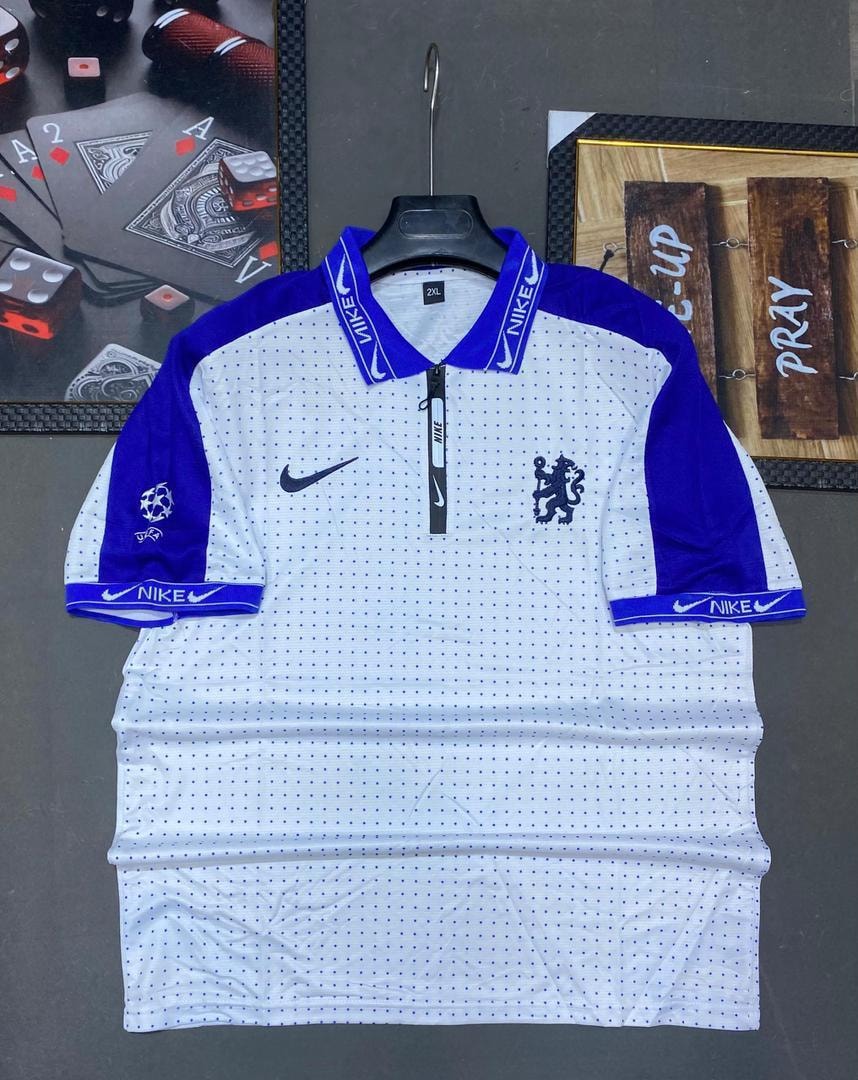 White and blue dotted Nike Chelsea polo jersey on flat surface.