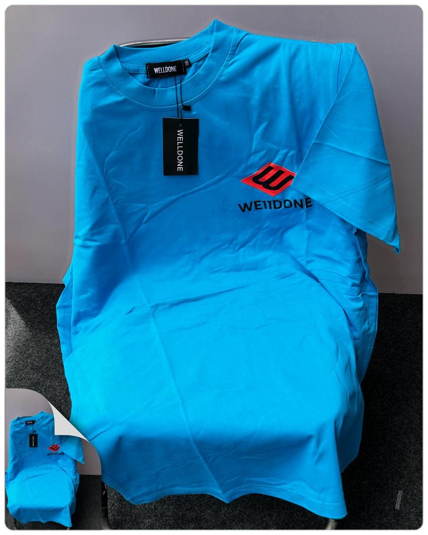 Bright blue Welldone logo t-shirt laid flat on chair.