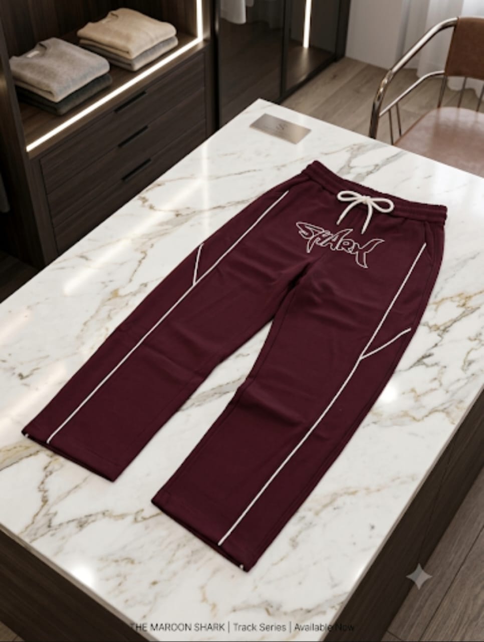 Maroon joggers with white SHARK script logo and contrast piping displayed on marble.