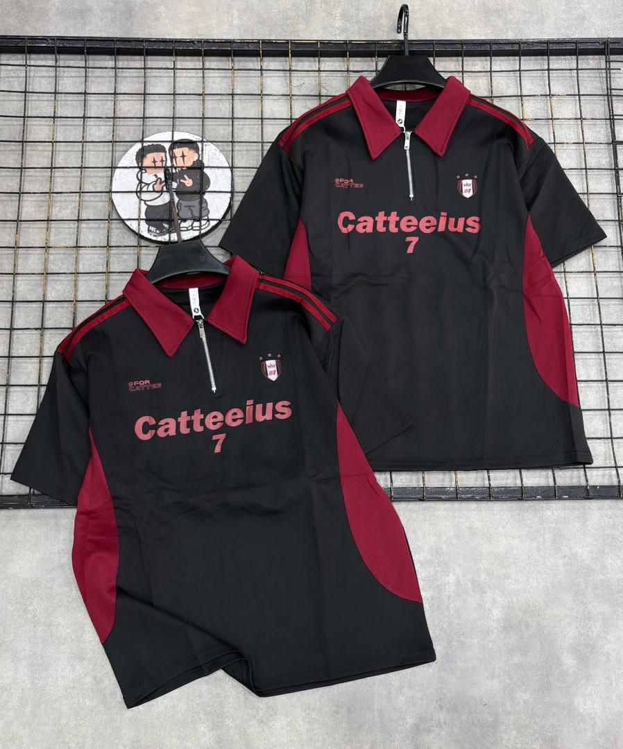 Black and maroon zip polo shirt with Catteeius 7 print and matching shorts on hangers and flat lay.
