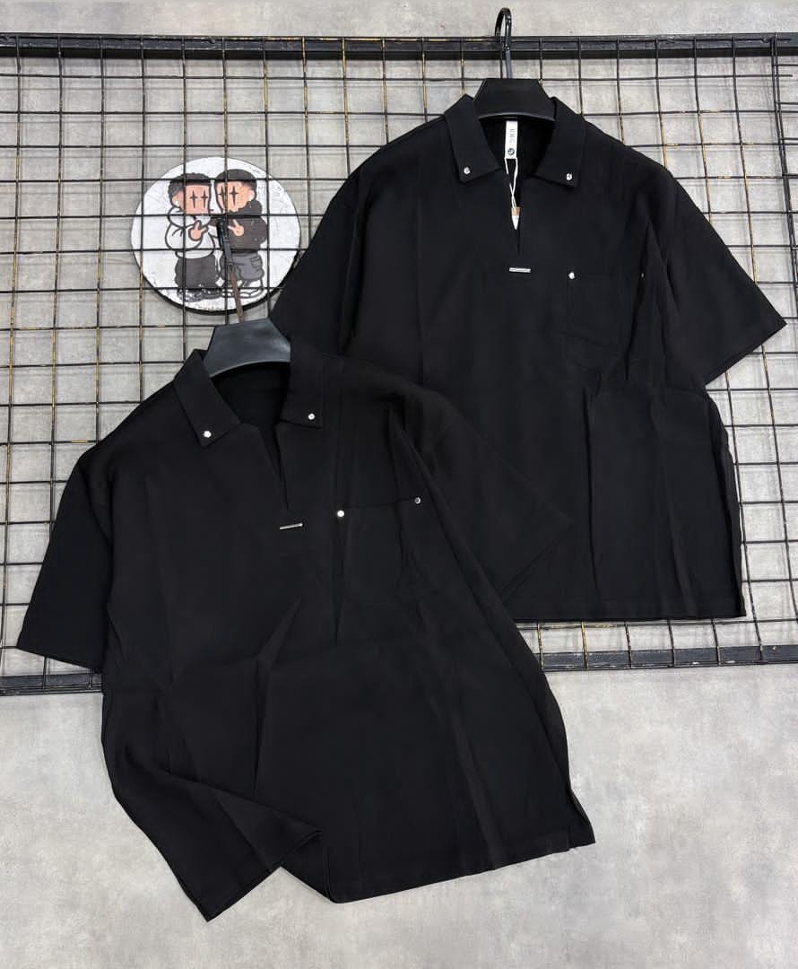 Two angles of black short sleeve collared shirt with pocket on wire grid background.