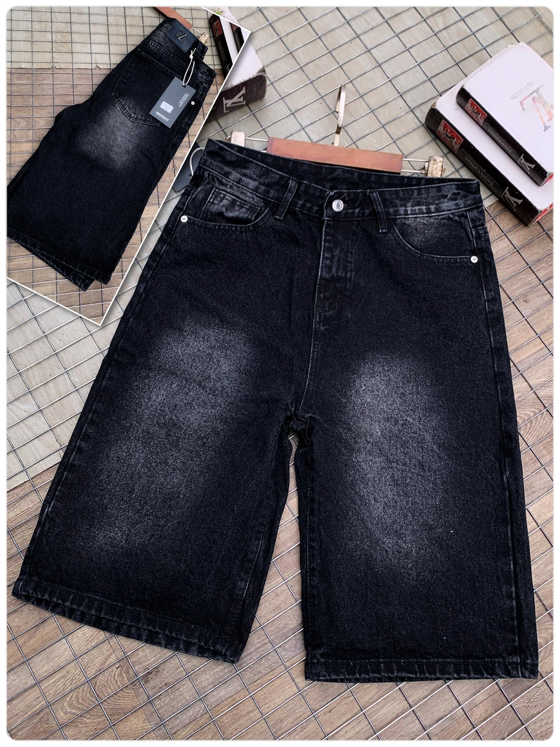 Black baggy jeans laid flat on tiled floor showing front view with faded wash details and accessories.
