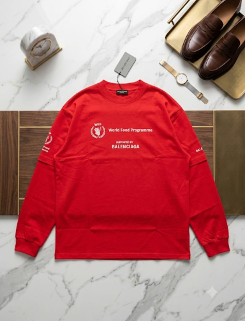 Red Balenciaga WFP sweatshirt on marble surface with watch and shoes.