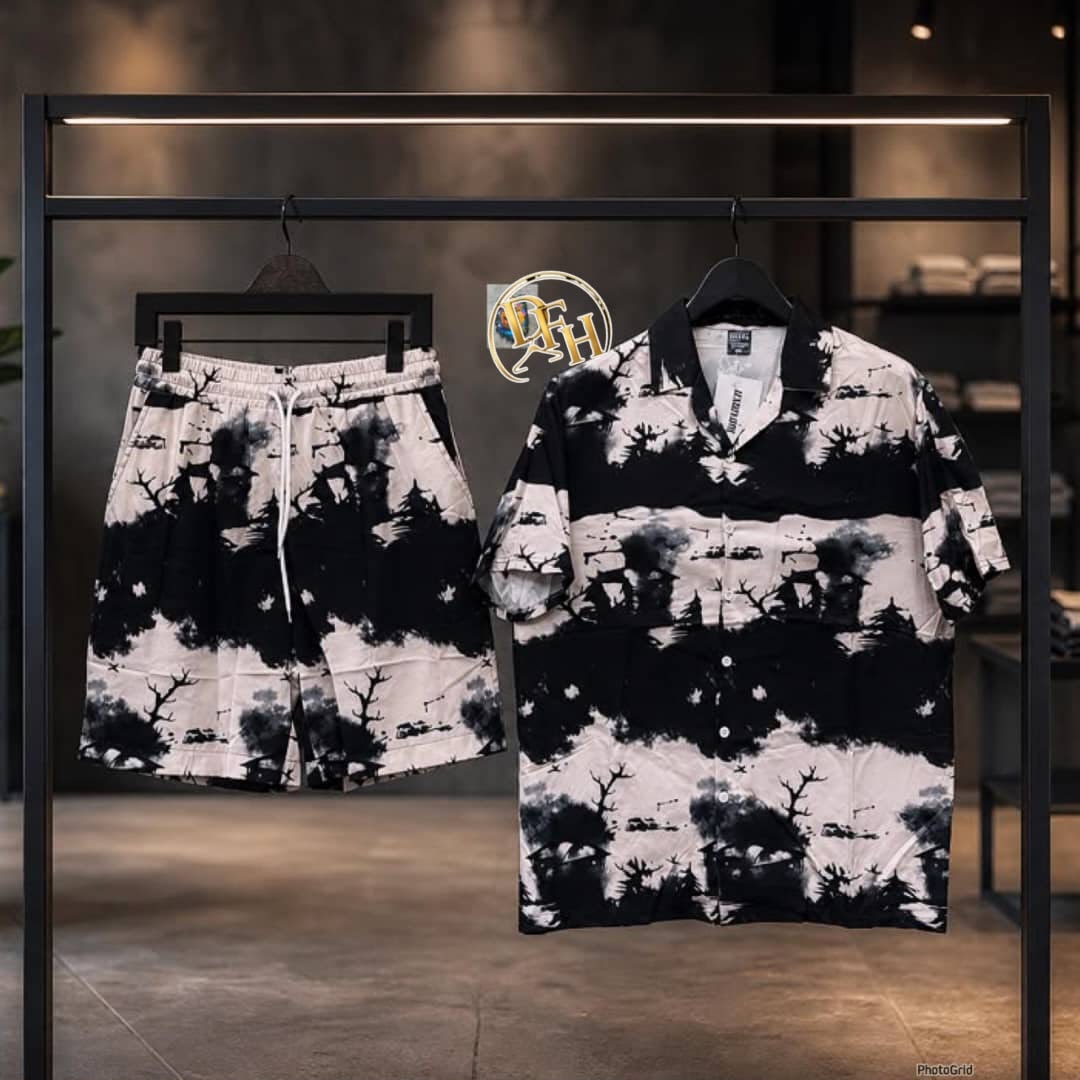 Black and white short sleeve shirt and shorts set with tree and landscape tie-dye print on metal rack.