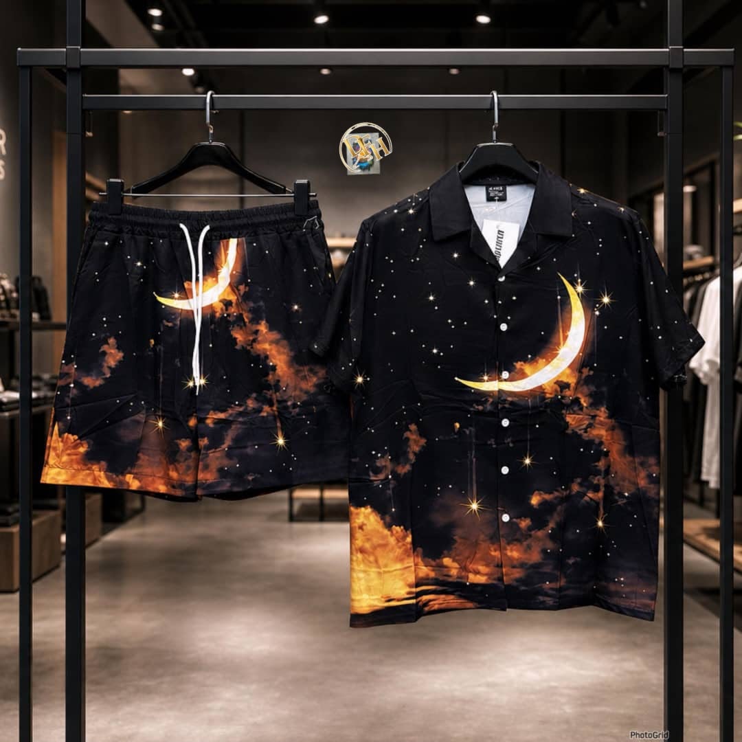 Black short sleeve shirt and shorts set with orange moon stars and cloud print displayed on rack.