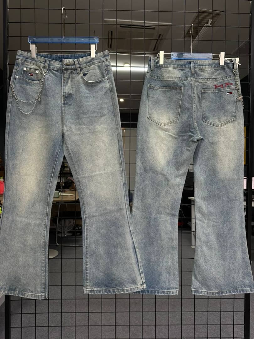 Light blue Tommy Hilfiger baggy jeans with chain on front pocket, hanging on rack.