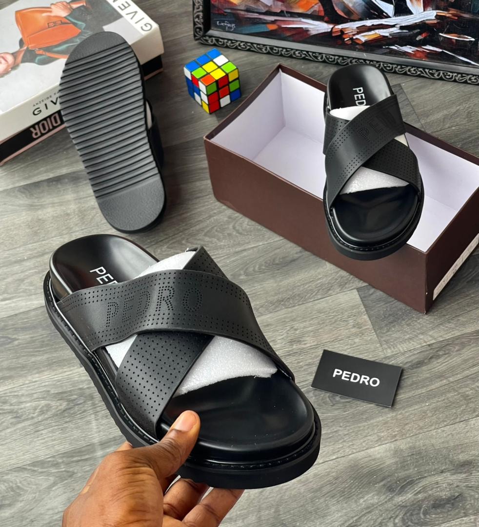Black cross strap slide with perforations and PEDRO branding, held in hand.