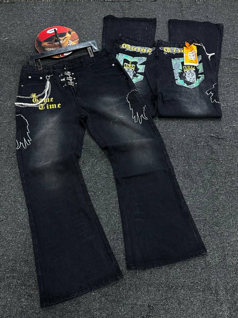 Flat lay of black Game Time baggy jeans with visible 'Game Time' text, wing design and skull patches.