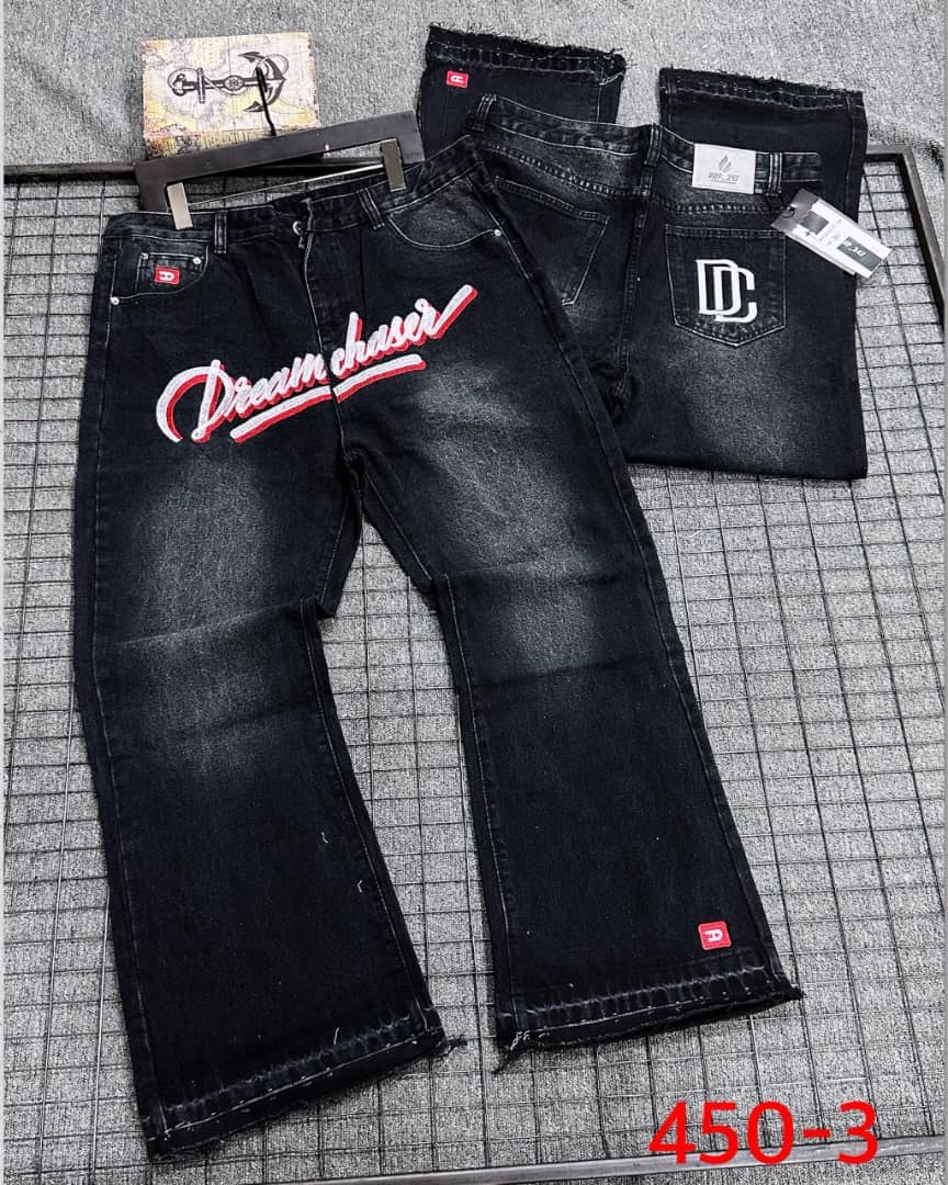 Flat lay of black Dreamchaser baggy jeans with 'Dreamchaser' script and DC logo details.